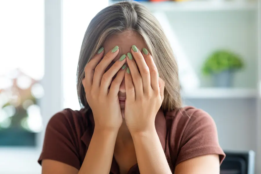 Frau hält sich mit beiden Händen das Gesicht
