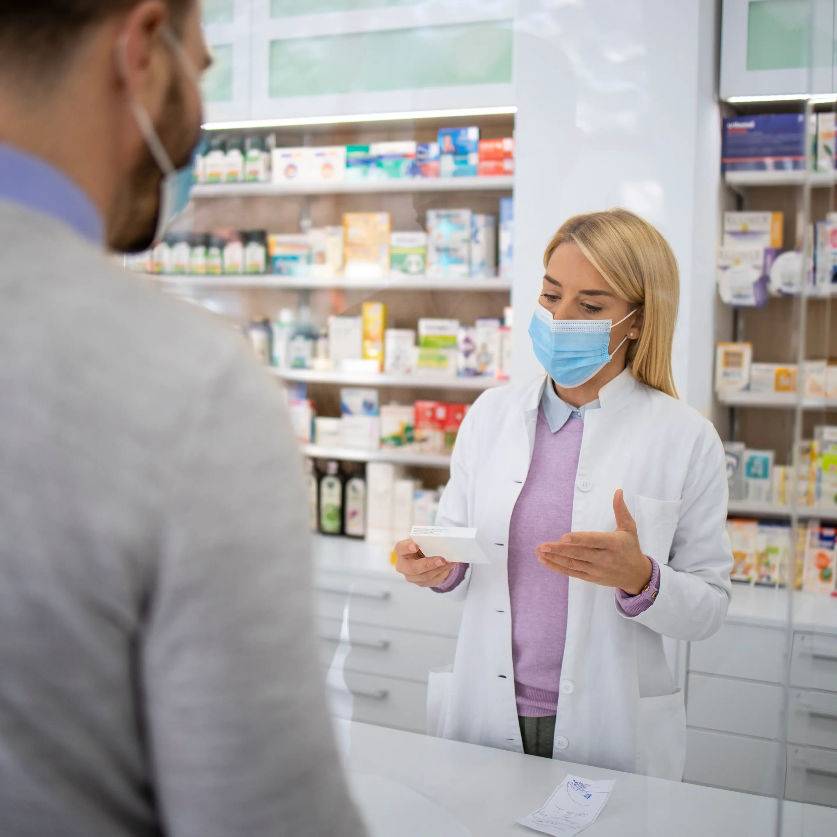 Apothekerin berät einen Kunden in einer Apotheke