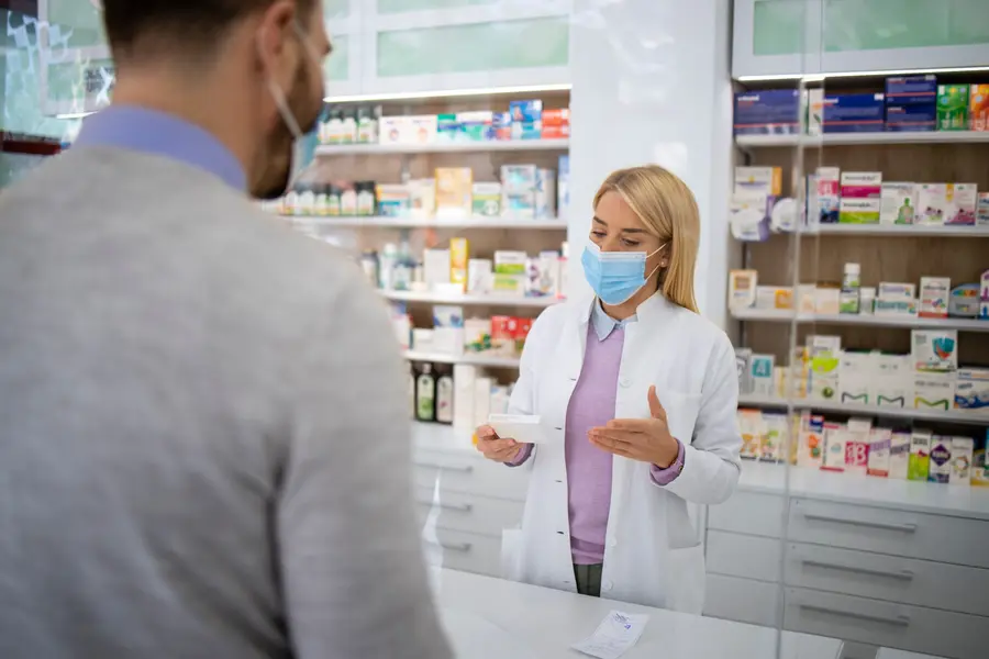 Apothekerin berät einen Kunden in einer Apotheke