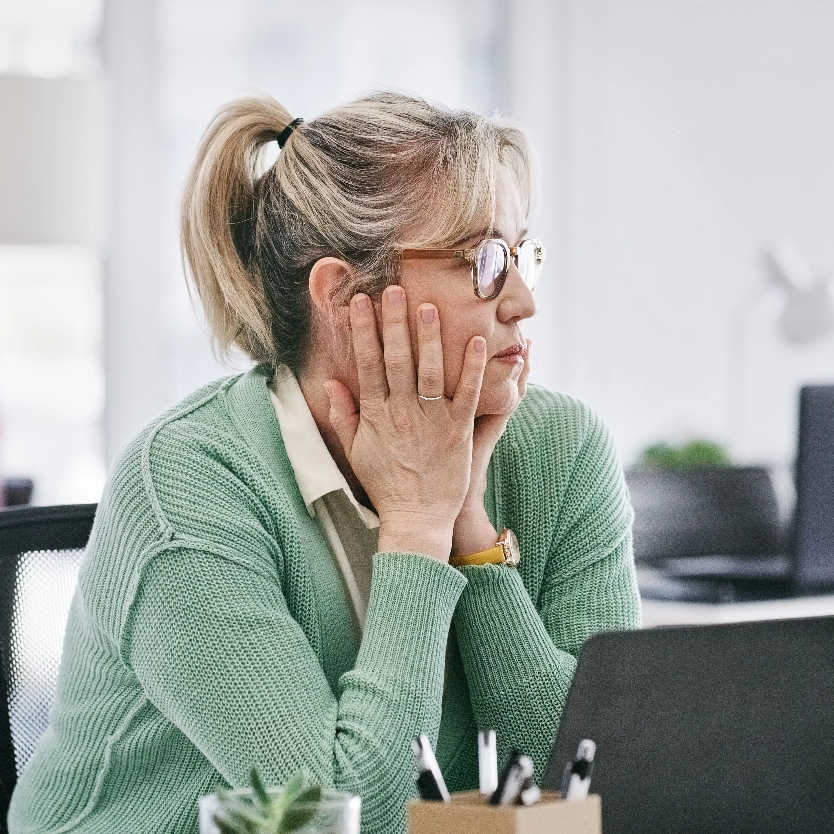 Eine Frau sitzt nachdenklich vor ihrem Computer im Büro.