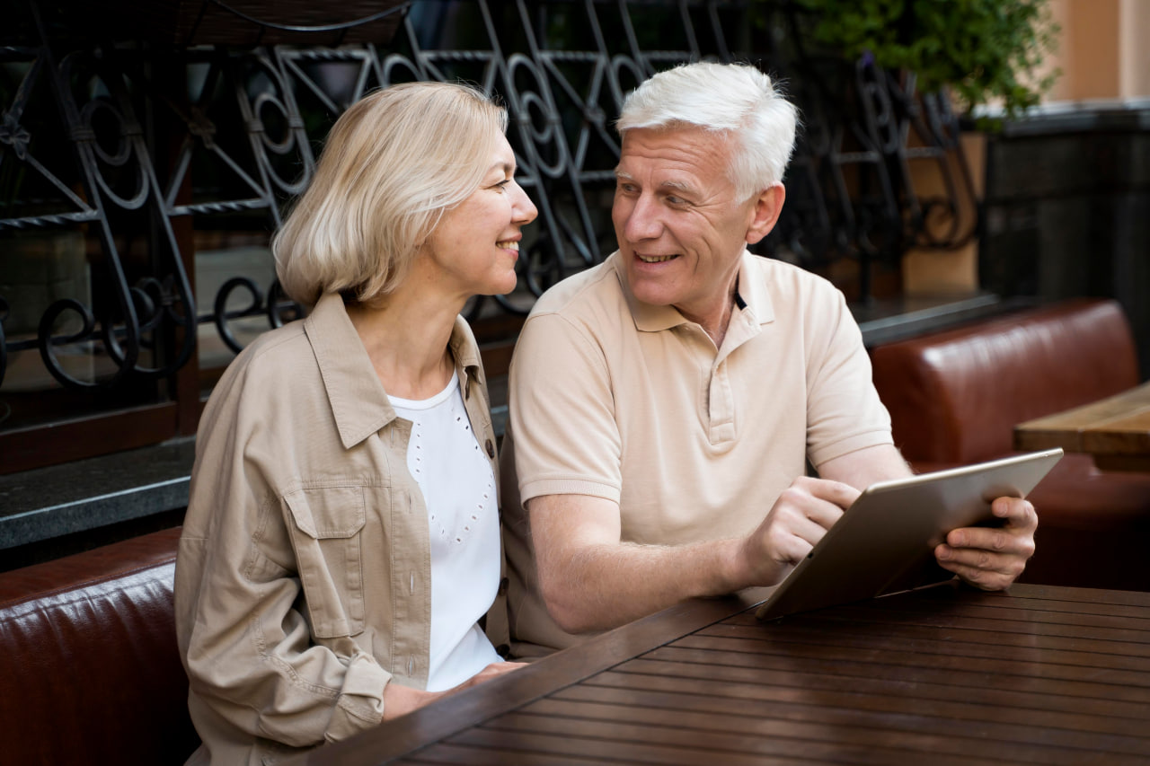 Happy couple over 50 using a digital tablet outdoors