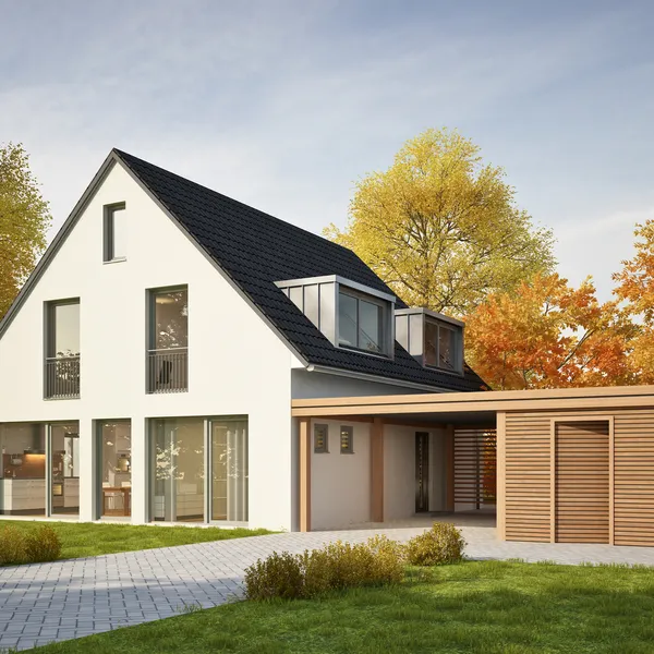 Modernes Einfamilienhaus mit Satteldach, großen Fenstern und separatem Holzcarport, umgeben von herbstlichen Bäumen und einem gepflegten Rasen.