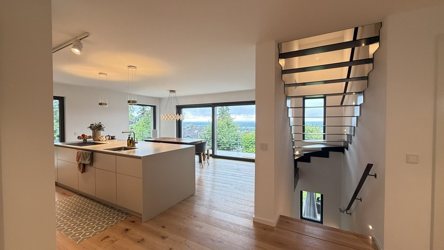 Wohnhaus SCHW — offene Wohnküche mit skulpturaler Treppe und Fernblick