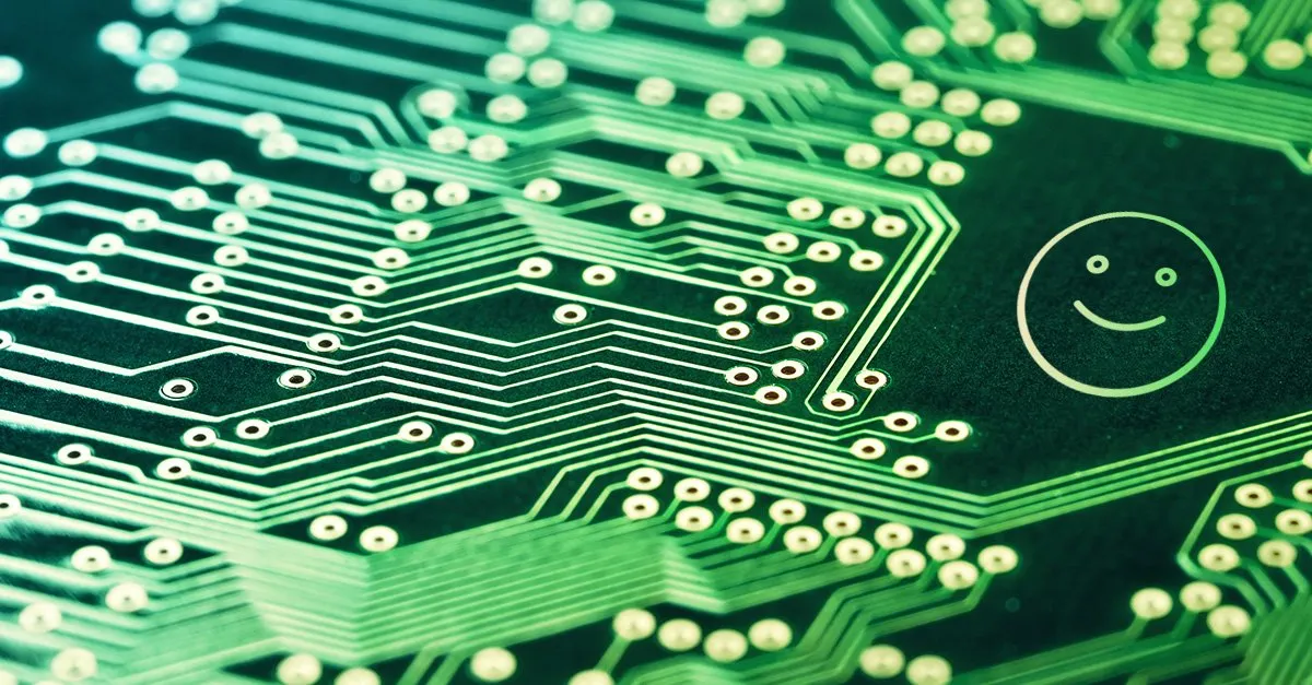 Close-up of a green circuit board with a smiley face etched into the copper traces