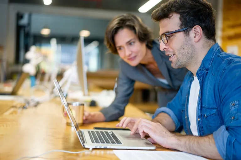 two employees collaborating on a laptop project