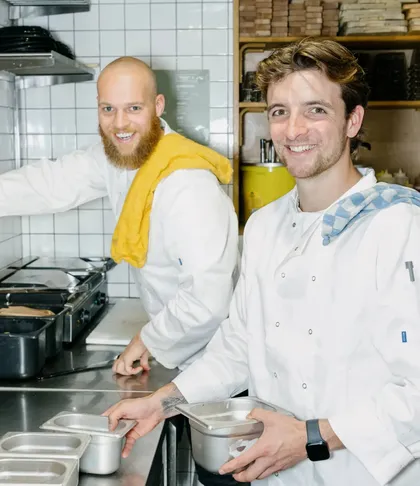 Twee koks die lachen in de restaurantkeuken