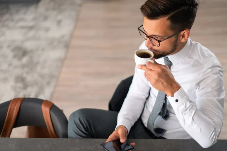 Jeune homme d'affaires buvant un café au travail le matin