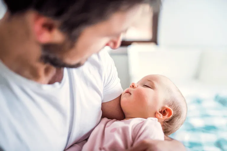 Father on paternity leave holding newborn