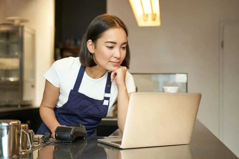 Smiling Asian girl barista working in cafe