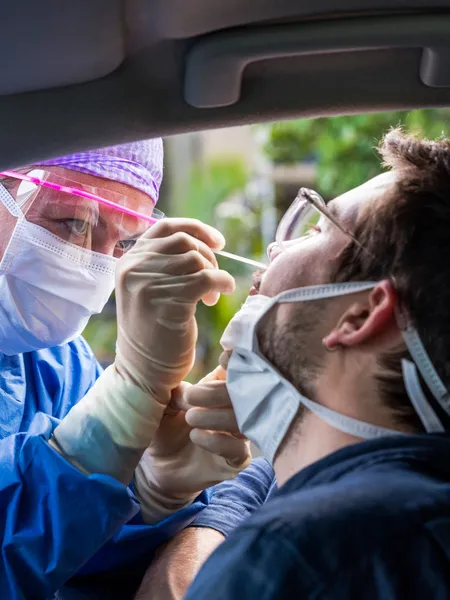 Health worker taking a test at a drive-through test site
