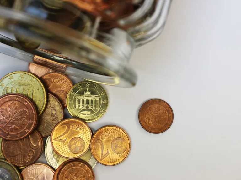 Euromunten voor de 13e maand die uit een pot op tafel zijn gevallen
