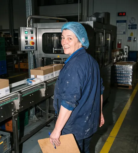 Production supervisor checking the line, clipboard in hand