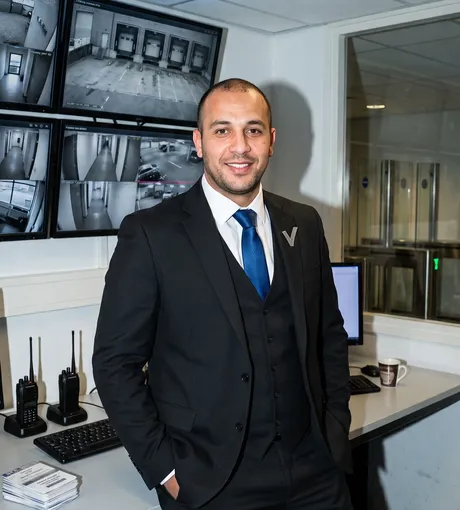 Security manager in the control room, camera wall behind him