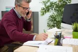 Manager on the phone filling in a return to work form at his desk