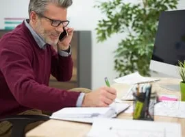 Manager on the phone filling in a return to work form at his desk