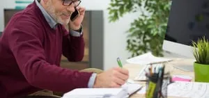 Manager on the phone filling in a return to work form at his desk