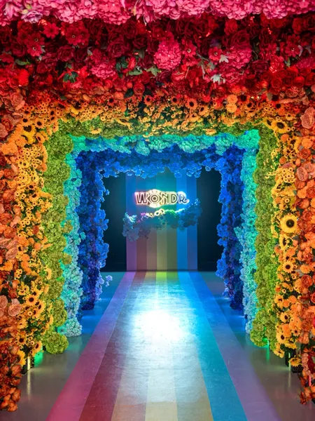 Bloemenboog in regenboogkleuren met het WONDR-neonbord bij WONDR Experience in Amsterdam