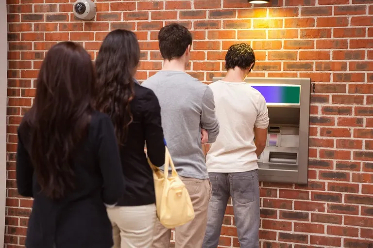 Jeunes faisant la queue au distributeur automatique de billets