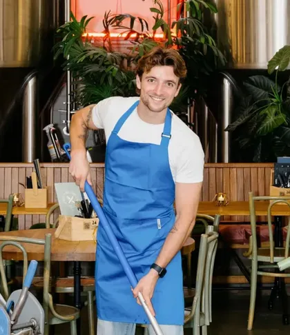 A cleaner in a blue apron mopping the floor
