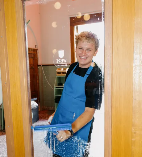 Cleaner squeegeeing the glass door of a café