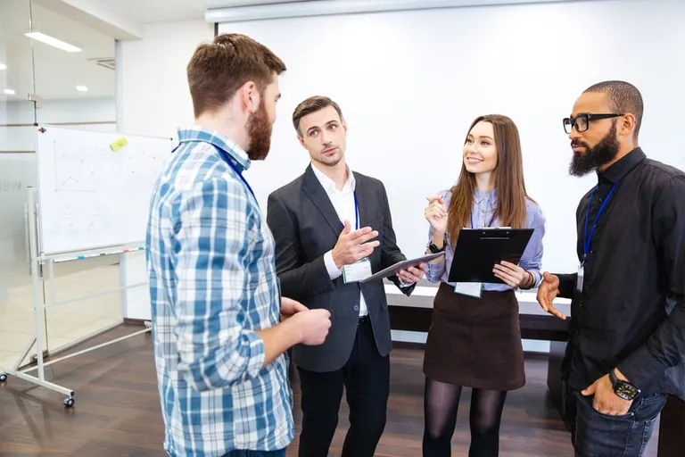 Manager speaking with smiling team members in an office