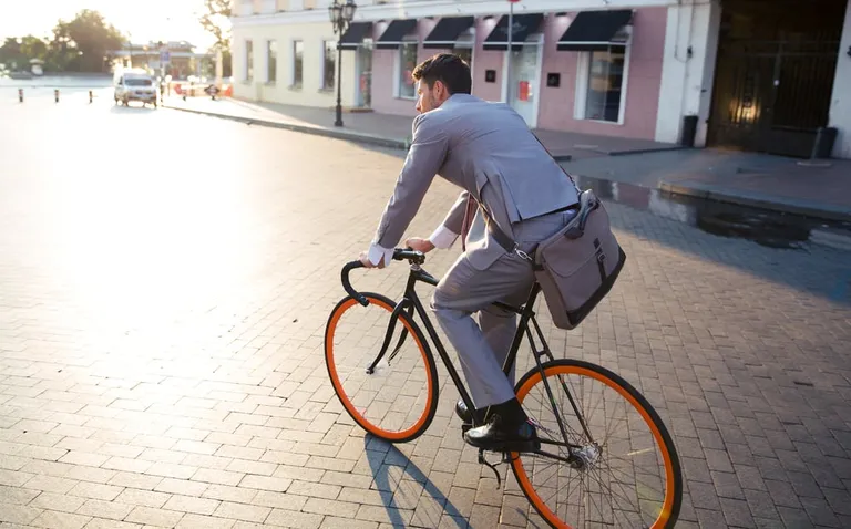 Businessman riding bicycle to work on urban street in morning-1