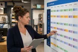 Een winkelmanager bekijkt het weekrooster van haar team op een planbord