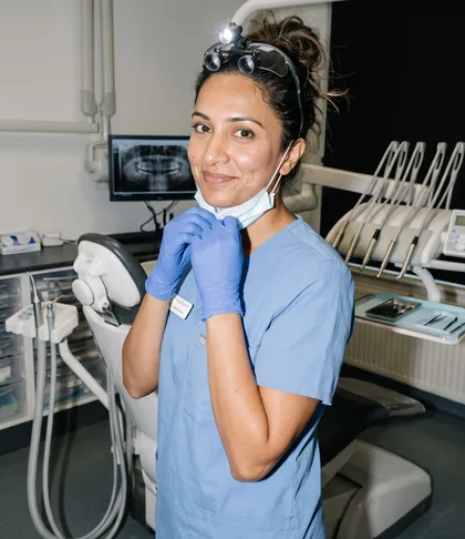 Una profesional sanitaria con uniforme azul y guantes en la sala de tratamiento