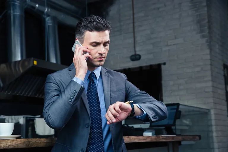 Cadre regardant sa montre au téléphone