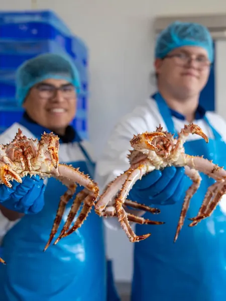 Two Fix Fisch employees holding up king crabs