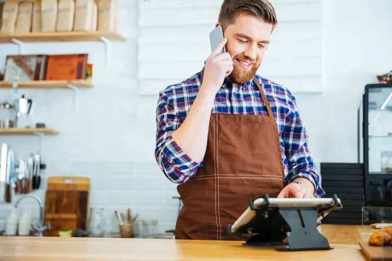 Barista souriant prenant une commande au téléphone avec une tablette
