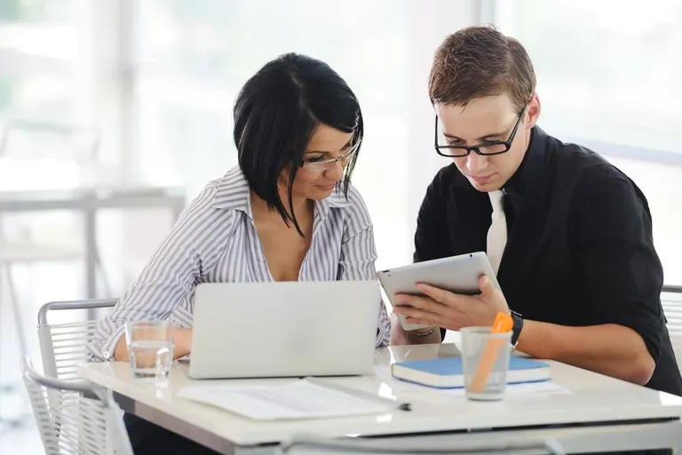 Three business people working with paperwork, tablet and laptop
