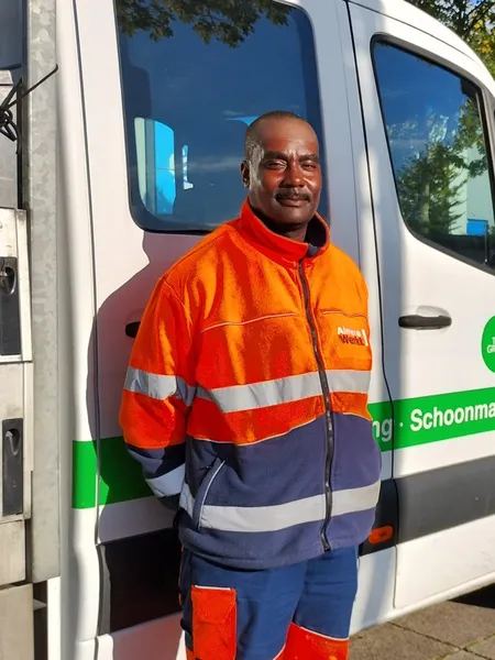 Tomingroep cleaner in high-vis next to the company van