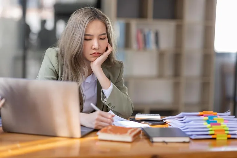Salariée au bureau avec des piles de documents