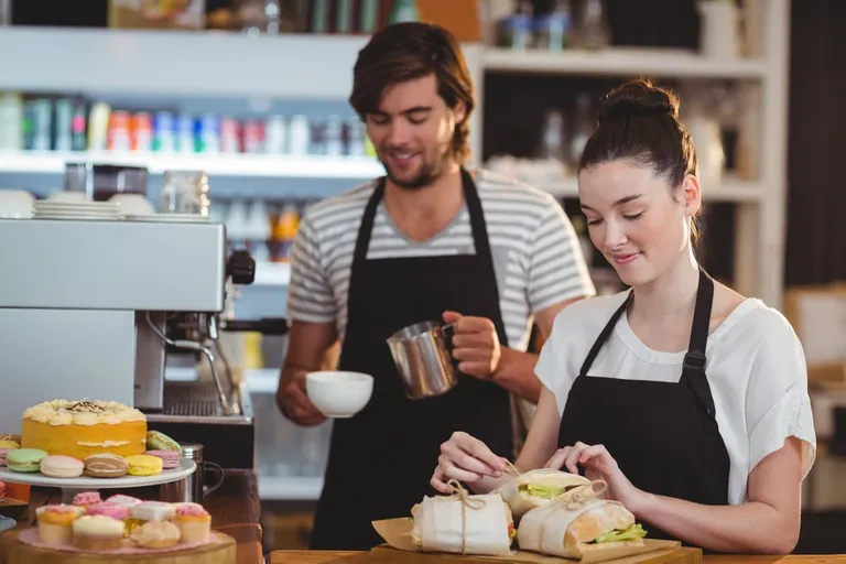 Serveur et serveuse au comptoir d’un café