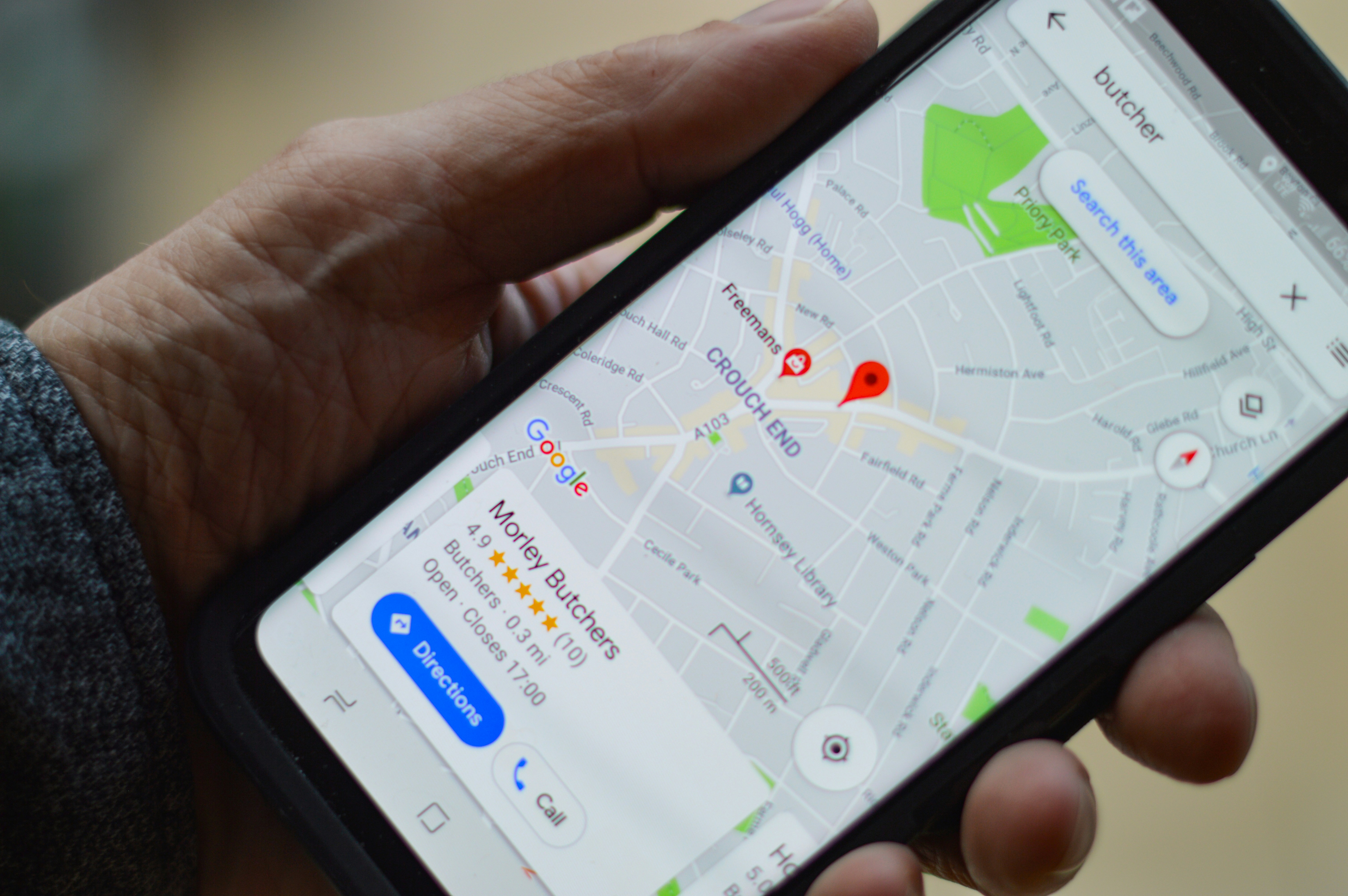 Person holding smartphone showing Google Maps local search results for a local butcher shop, illustrating local search and AEO for local businesses