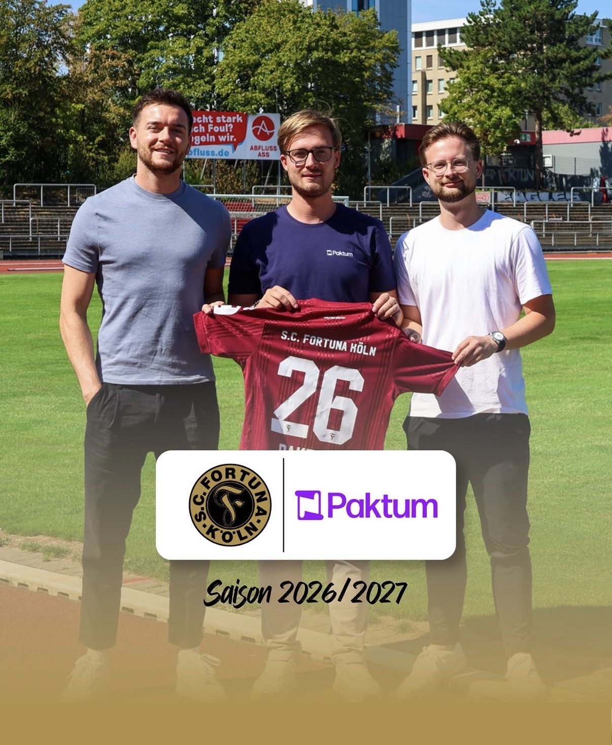 Trikotübergabe beim SC Fortuna Köln: Vertreter des Clubs und von Paktum mit einem roten Fortuna Trikot mit der Nummer 26 im Stadion, Saison 2026/2027