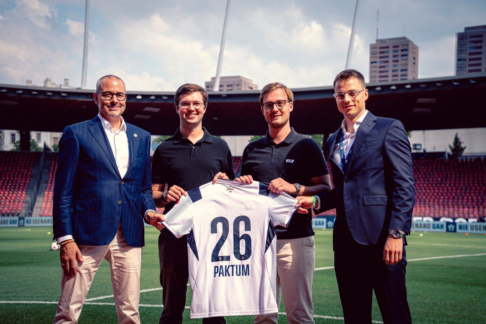 Trikotübergabe im Stadion: Vertreter des FC Zürich und von Paktum mit einem weissen FCZ Trikot mit der Nummer 26 und dem Schriftzug Paktum