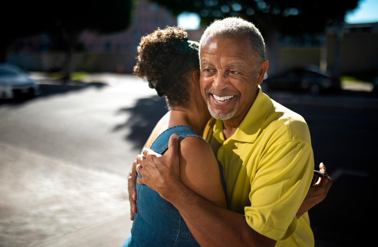 Smiling senior man hugging woman on sunny street