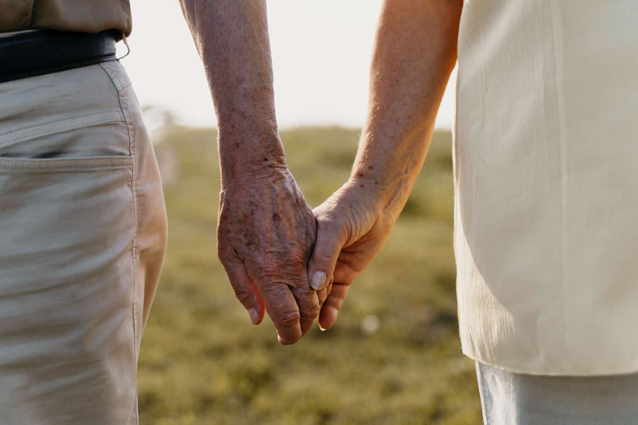 Close-up of senior couple holding hands outdoors