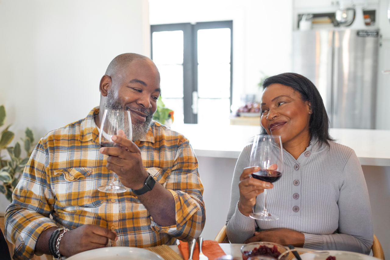 Black Senior couple toasting with wine glasses at dinner table