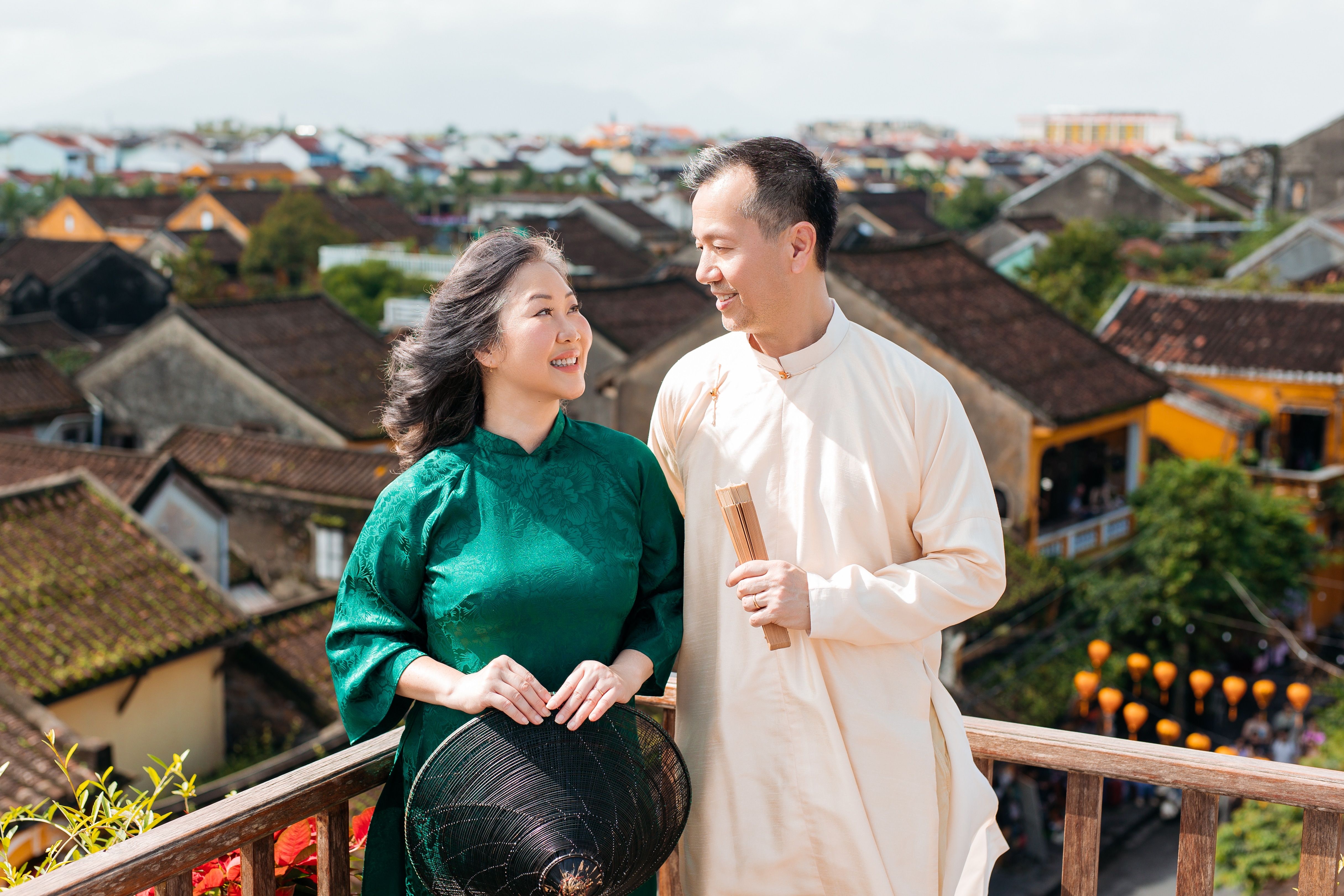 A couple in traditional attire standing on a rooftop balcony