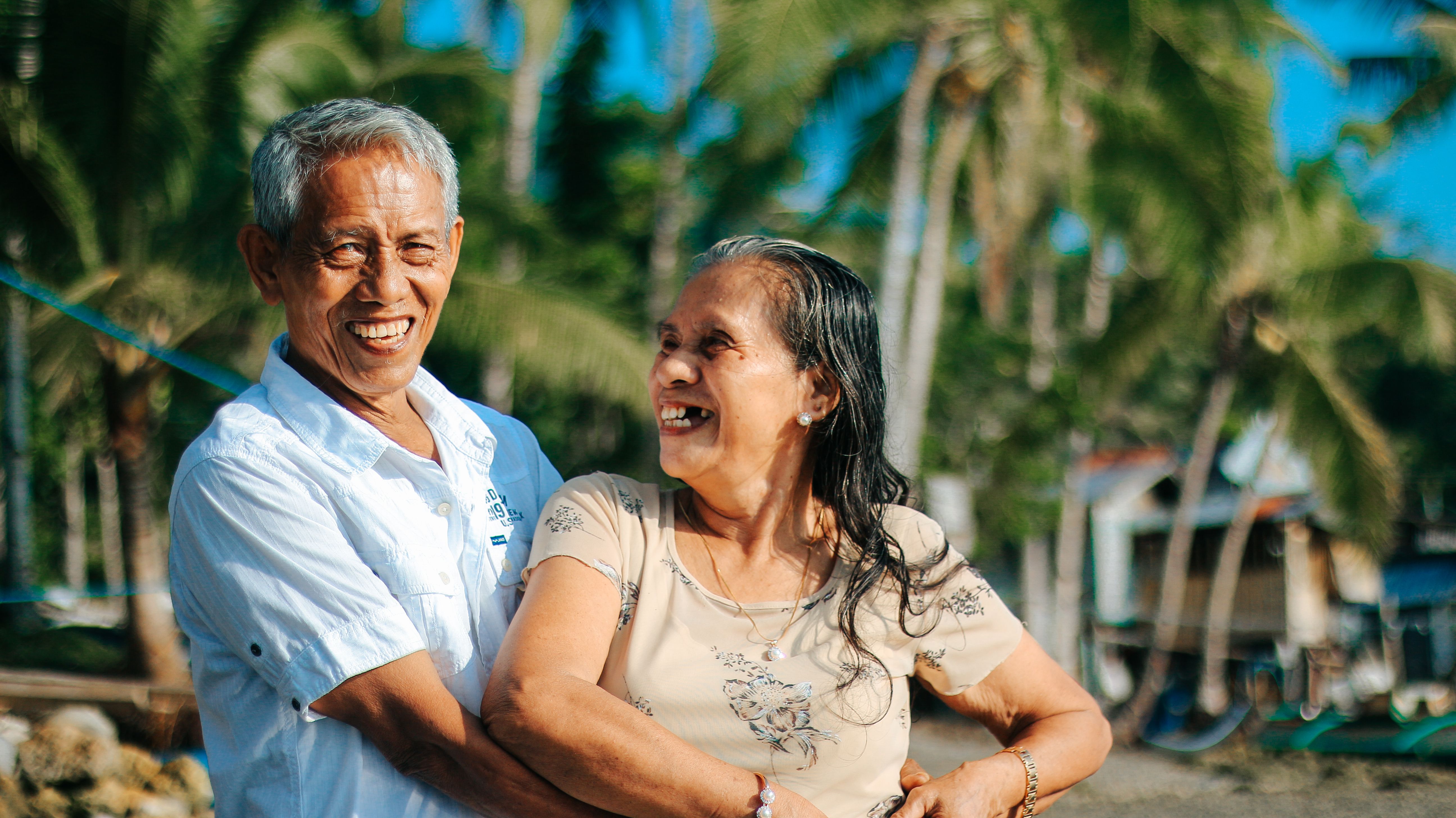 A joyful senior couple laughing together on a beach