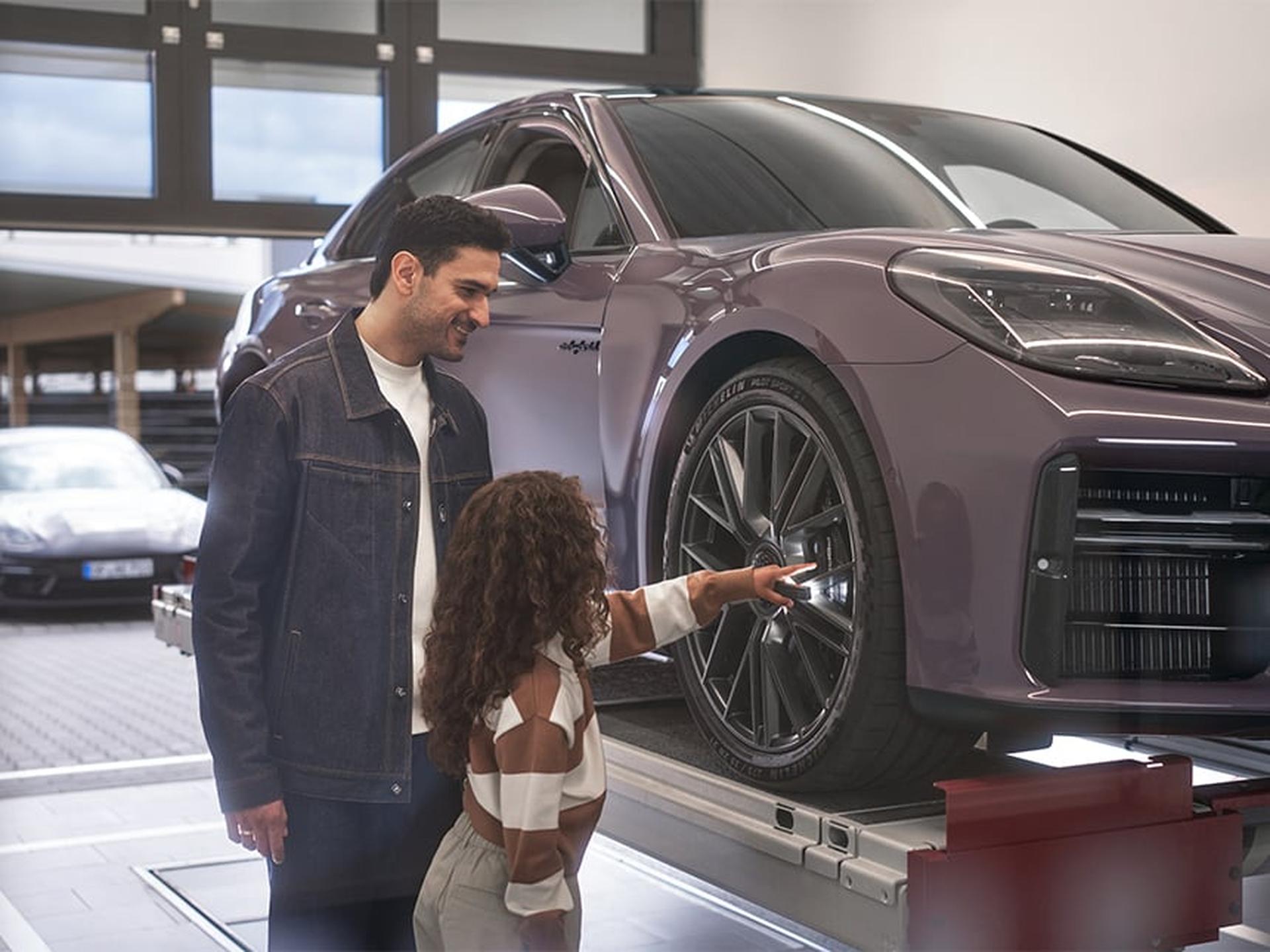 Ein Porsche Kunde zeigt während der Direktannahme seinem Kind einen Porsche Sportwagen.