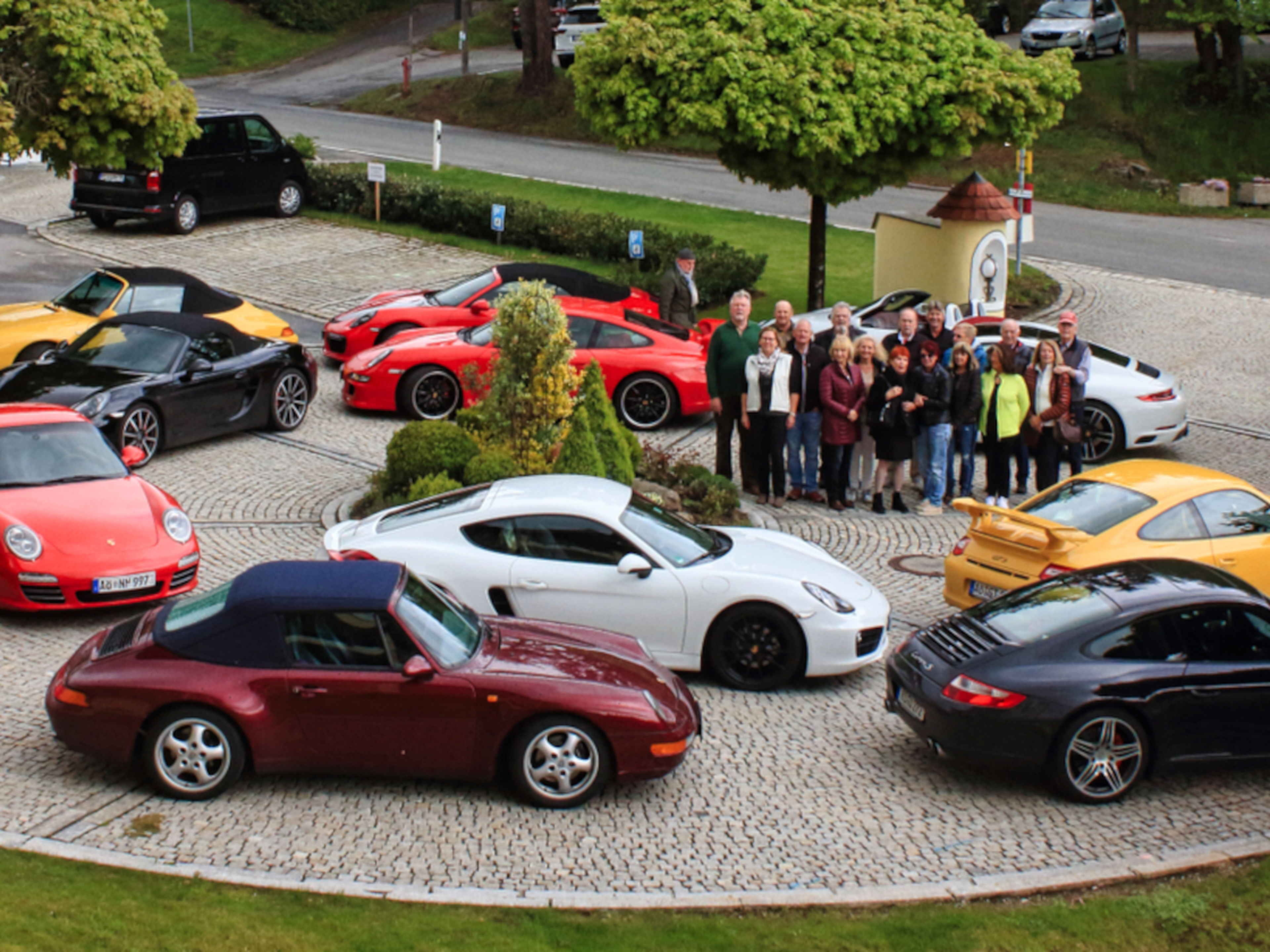 Mehrere Porsche fahren eine Serpentinenstraße entlang.