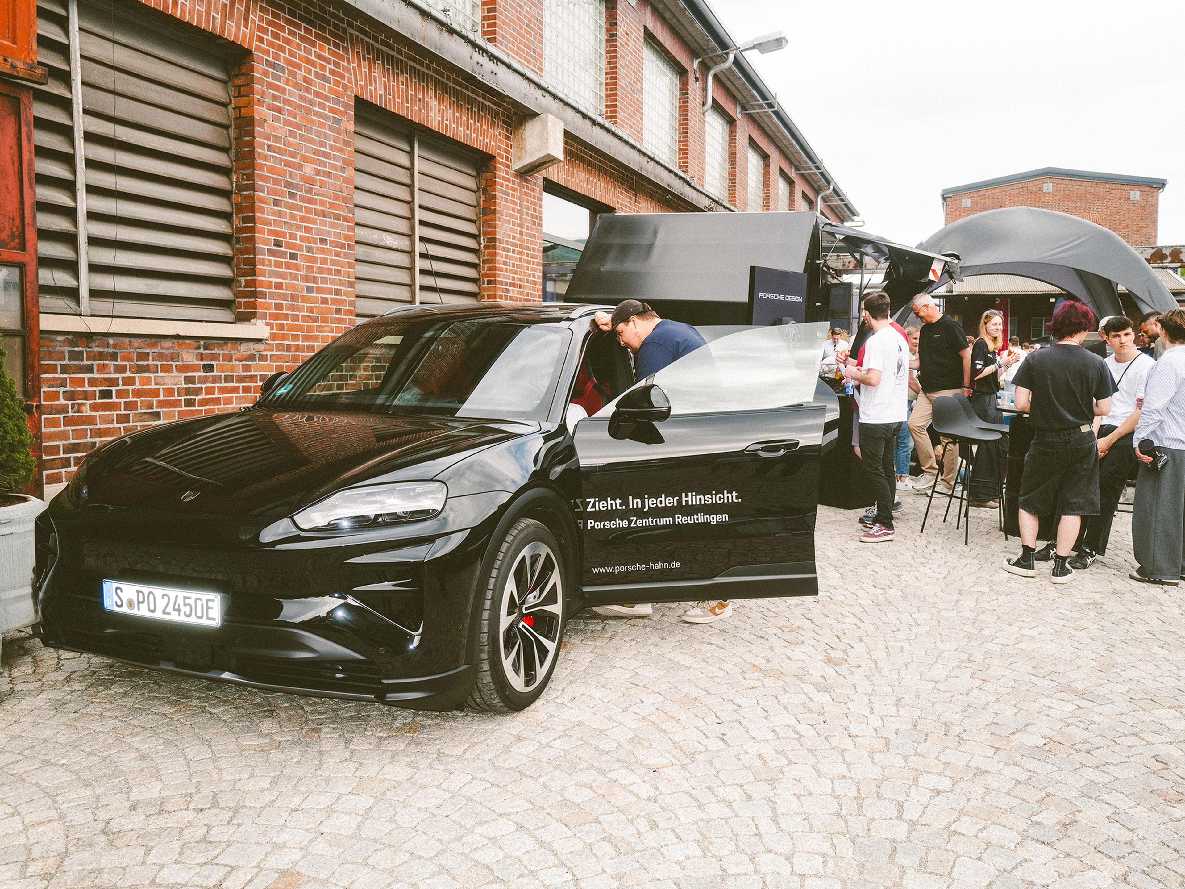 Ein Porsche Fahrzeug auf einem Hof mit Menschen drumherum