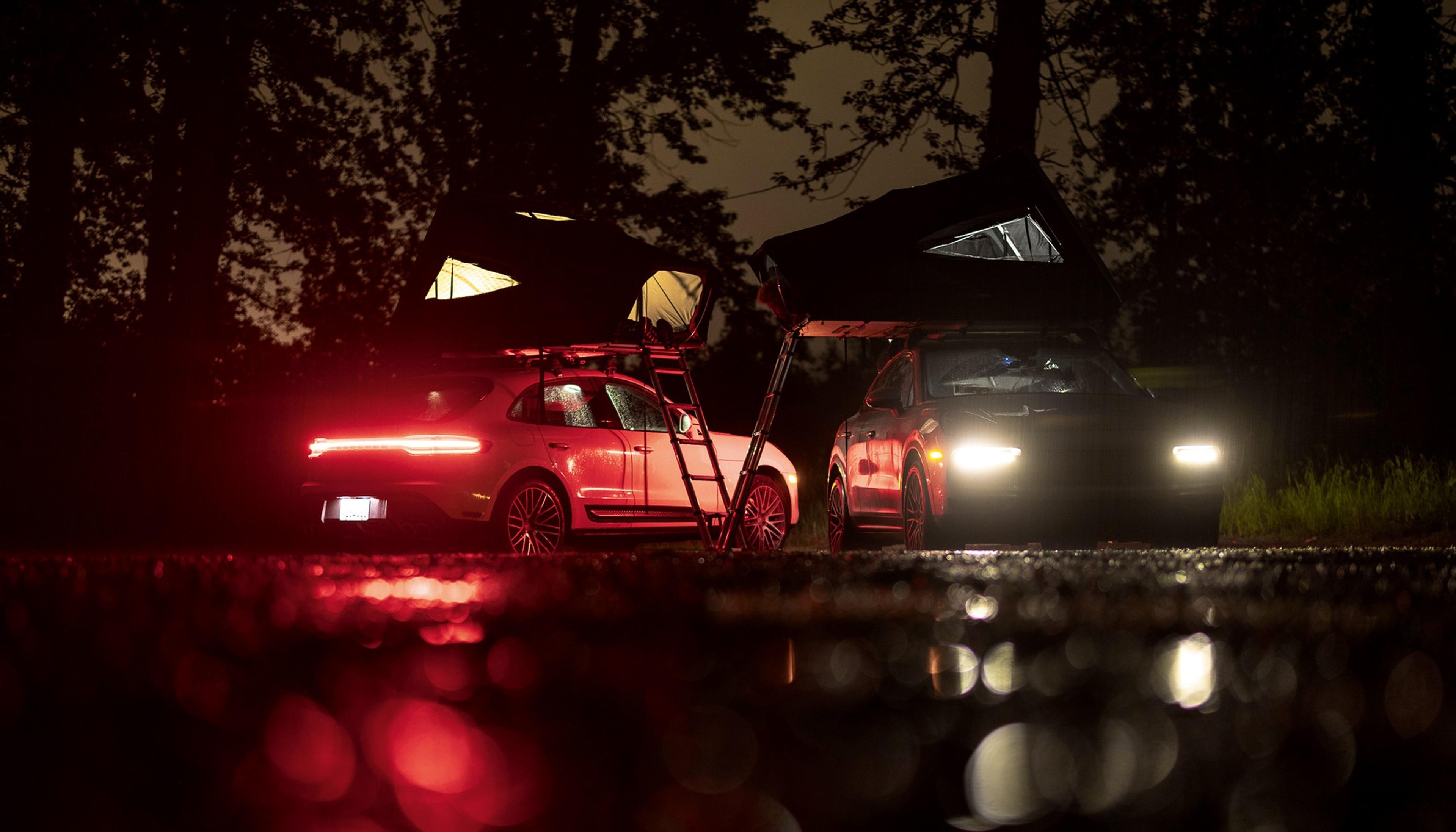 Zwei Porsche Fahrzeuge mit Dachzelt bei Nacht.