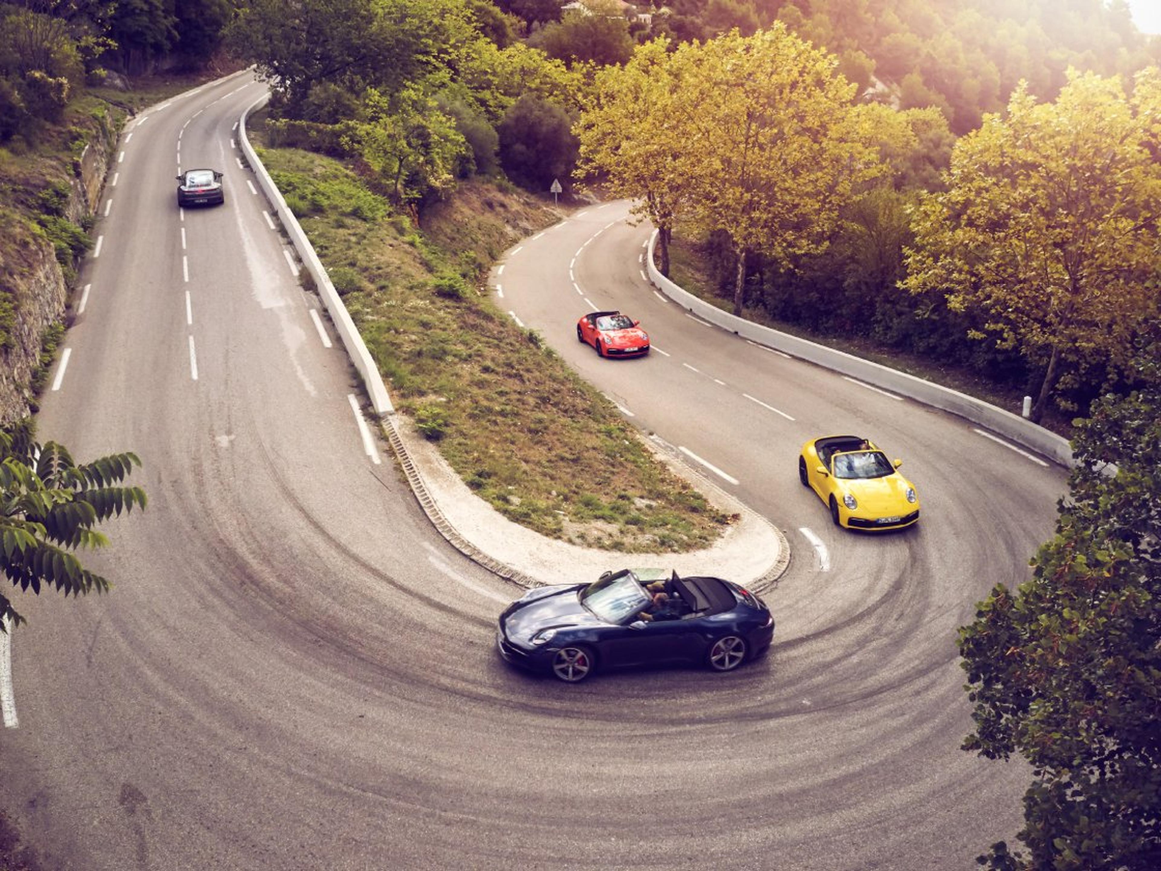 Mehrere Porsche fahren eine Serpentinenstraße entlang.