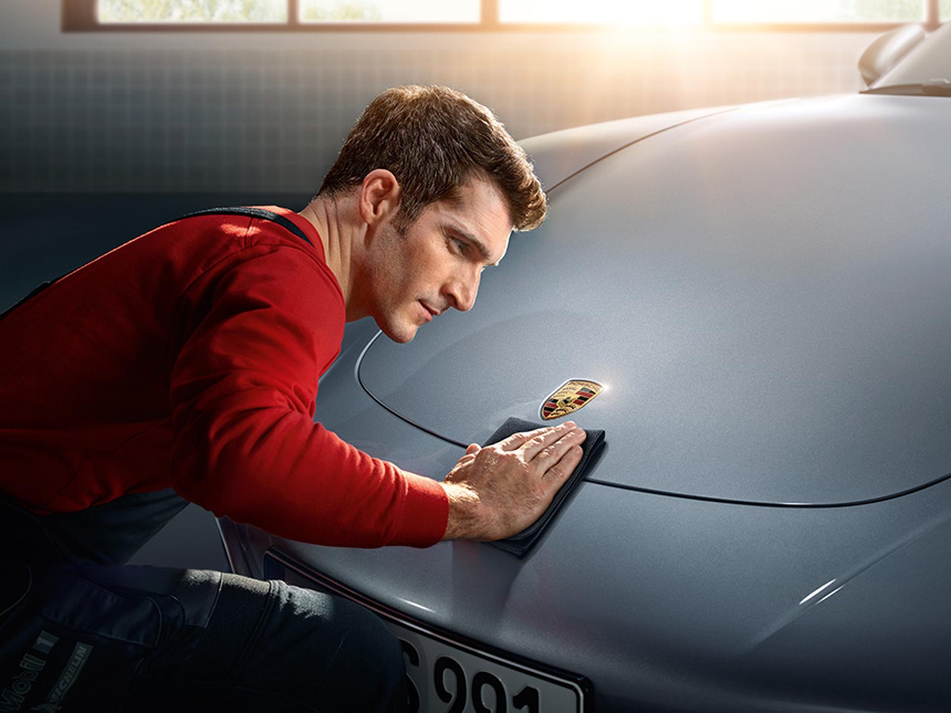 Mechaniker poliert die Motorhaube.