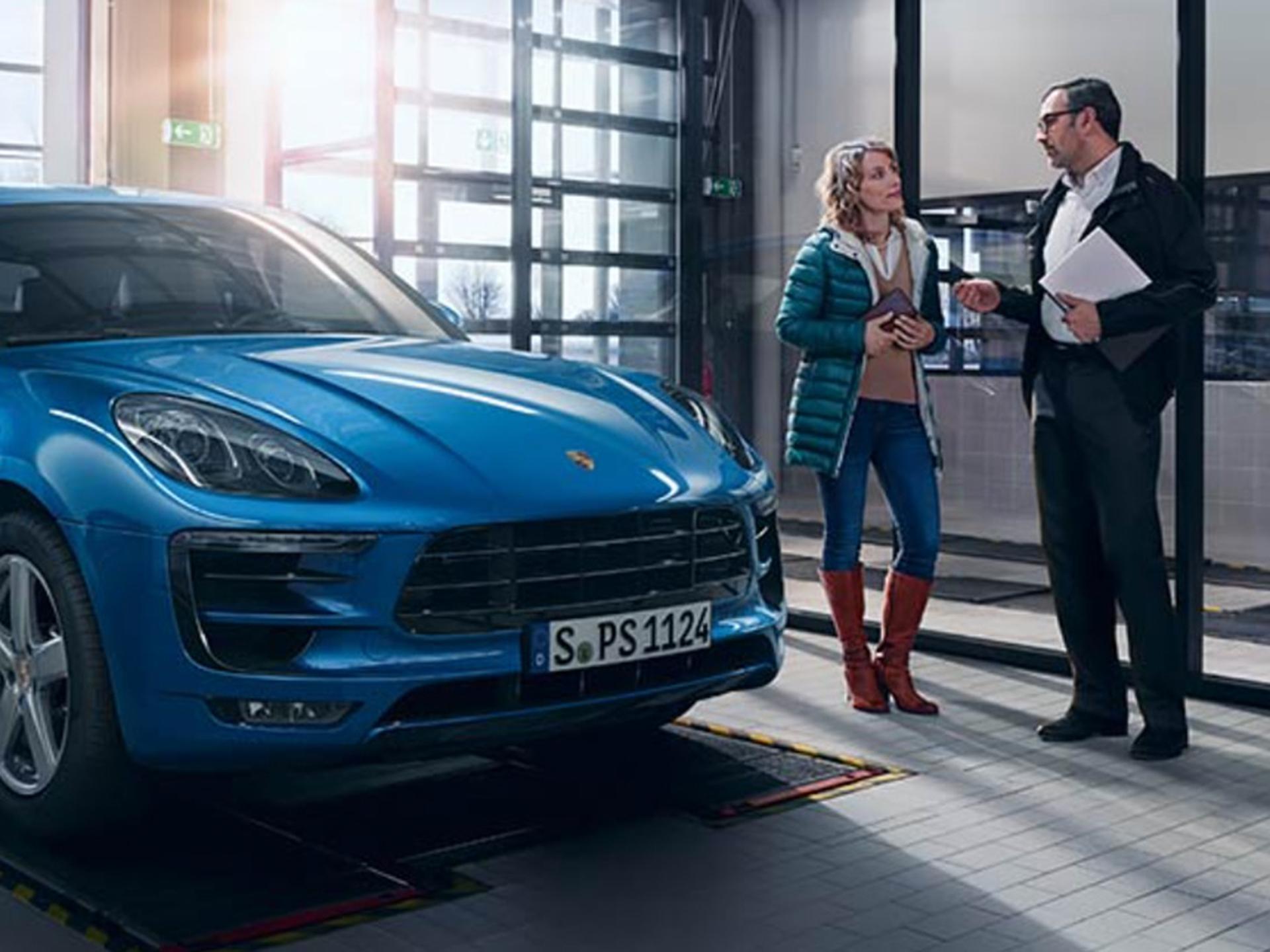 Porsche Mitarbeiter im Gespräch mit Kundin im Fahrzeug-Annahmebereich.